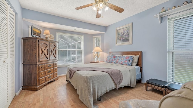 bedroom featuring a textured ceiling, light hardwood / wood-style floors, ceiling fan, and a closet