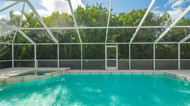 view of pool with glass enclosure and an in ground hot tub