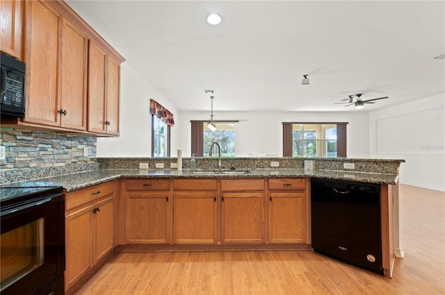 kitchen featuring black appliances, dark stone countertops, kitchen peninsula, and sink