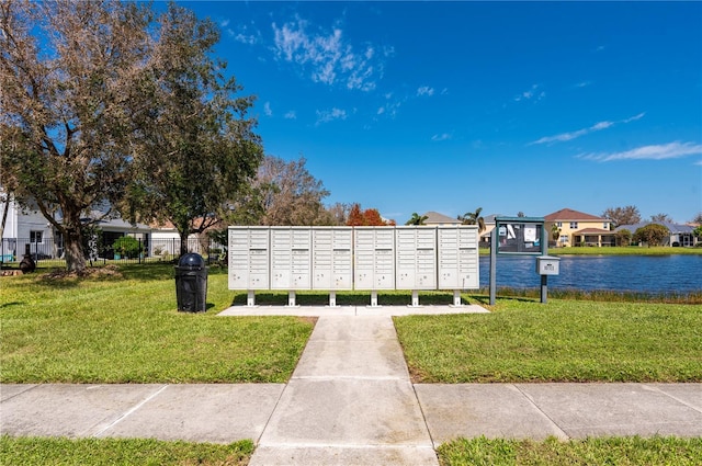 view of community featuring mail boxes, a water view, and a lawn