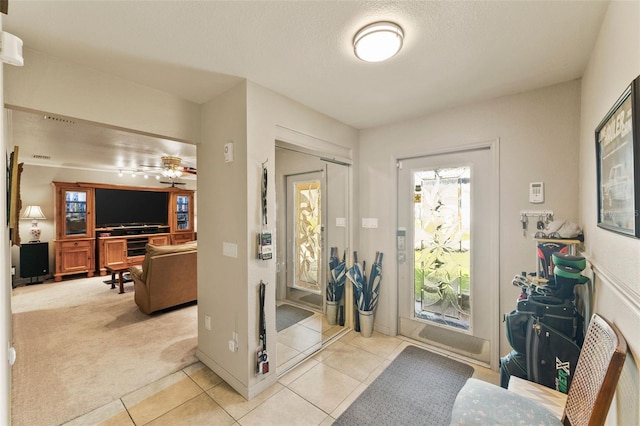 foyer featuring a textured ceiling, light colored carpet, and ceiling fan