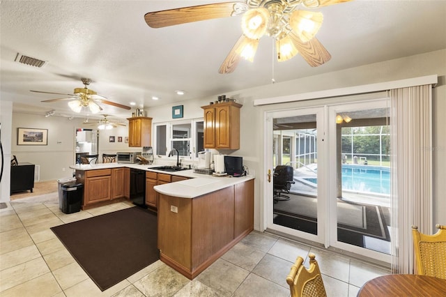 kitchen with black dishwasher, kitchen peninsula, sink, light tile patterned floors, and ceiling fan