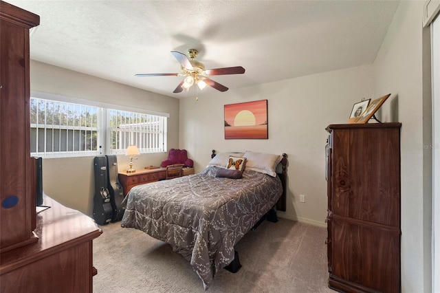 bedroom featuring a textured ceiling, light colored carpet, and ceiling fan