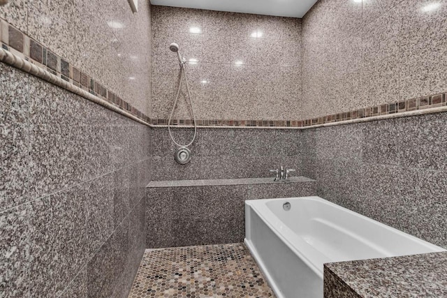 bathroom featuring a bath and tile walls