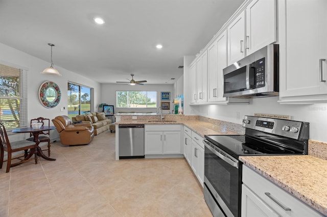 kitchen with kitchen peninsula, hanging light fixtures, appliances with stainless steel finishes, white cabinetry, and sink