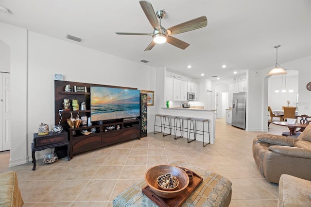 tiled living room with sink and ceiling fan with notable chandelier