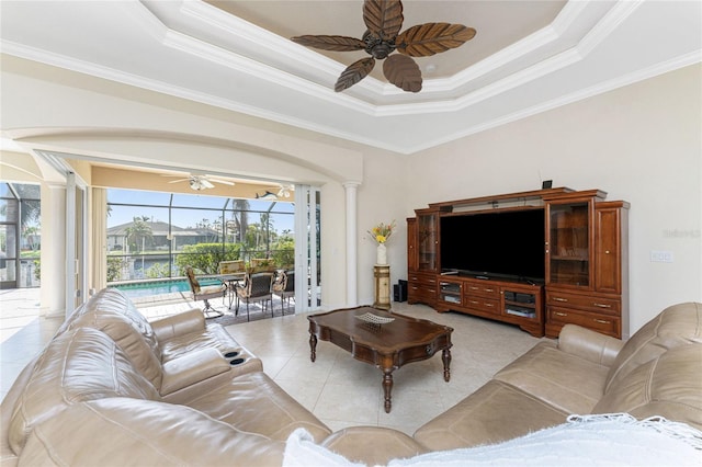 living room featuring ceiling fan, a tray ceiling, ornate columns, and ornamental molding