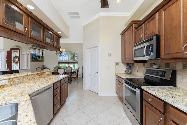 kitchen featuring stainless steel appliances, light stone countertops, light tile patterned floors, backsplash, and crown molding