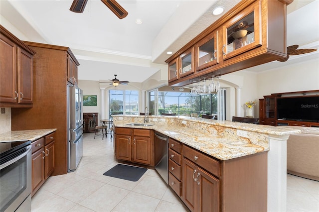 kitchen with sink, light tile patterned floors, crown molding, light stone countertops, and appliances with stainless steel finishes