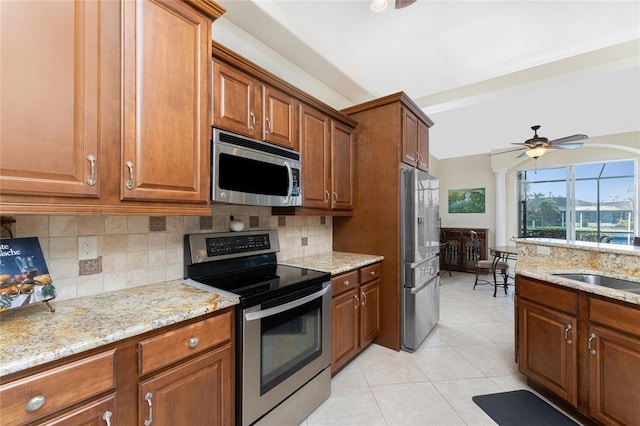 kitchen featuring light stone counters, light tile patterned flooring, stainless steel appliances, decorative backsplash, and ceiling fan