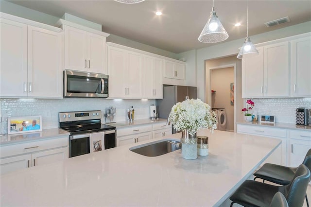 kitchen featuring pendant lighting, a breakfast bar, appliances with stainless steel finishes, white cabinetry, and decorative backsplash