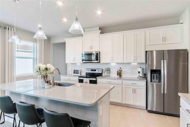 kitchen with sink, white cabinetry, hanging light fixtures, an island with sink, and stainless steel appliances