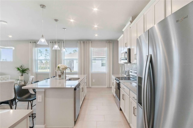 kitchen with white cabinetry, appliances with stainless steel finishes, a center island with sink, and pendant lighting