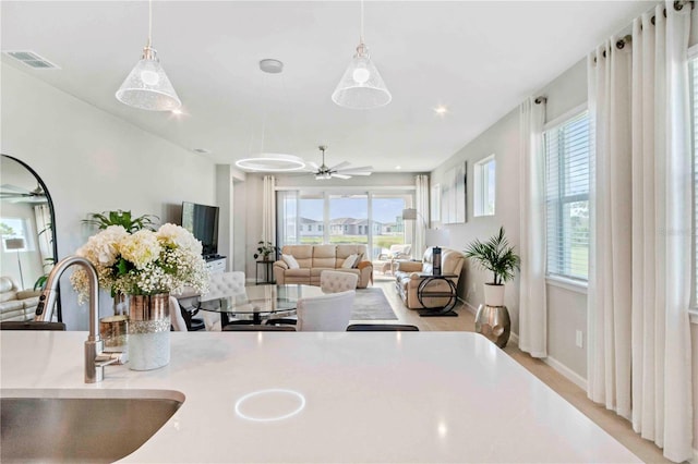 kitchen featuring ceiling fan, a healthy amount of sunlight, sink, and hanging light fixtures