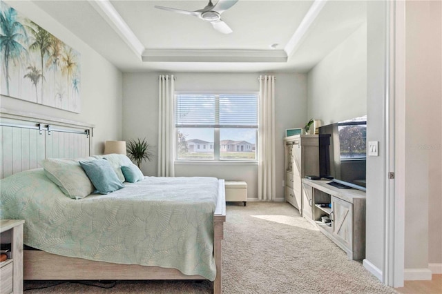 bedroom featuring ceiling fan, light colored carpet, ornamental molding, and a tray ceiling