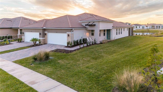 view of front of property featuring a water view, a garage, and a lawn