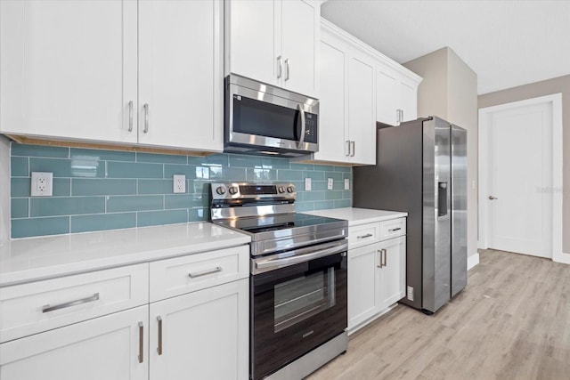 kitchen featuring decorative backsplash, white cabinets, stainless steel appliances, and light hardwood / wood-style floors