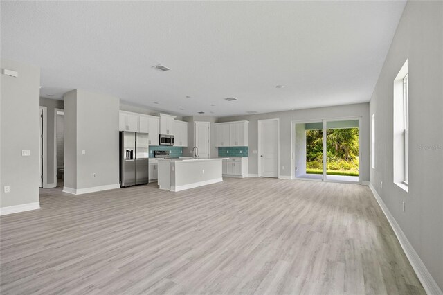 2404 Hanford Ln, North Port, FL 34288 - unfurnished living room with visible vents, a sink, light wood-style flooring, and baseboards