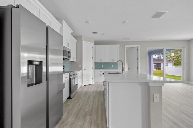 2404 Hanford Ln, North Port, FL 34288 - kitchen featuring visible vents, decorative backsplash, a sink, light wood finished floors, and stainless steel appliances