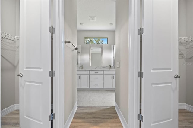 2404 Hanford Ln, North Port, FL 34288 - hallway with baseboards, a sink, light wood-style flooring, and visible vents