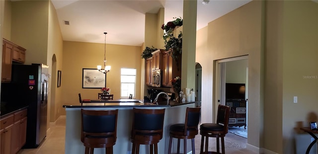 kitchen with a breakfast bar area, hanging light fixtures, kitchen peninsula, stainless steel appliances, and an inviting chandelier