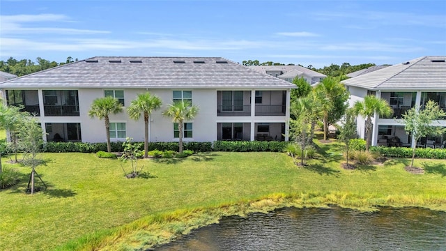 back of house with a water view and a lawn