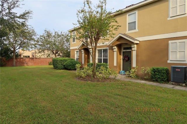 view of front of home featuring cooling unit and a front yard