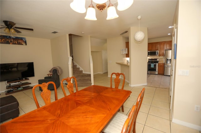 tiled dining area featuring ceiling fan with notable chandelier