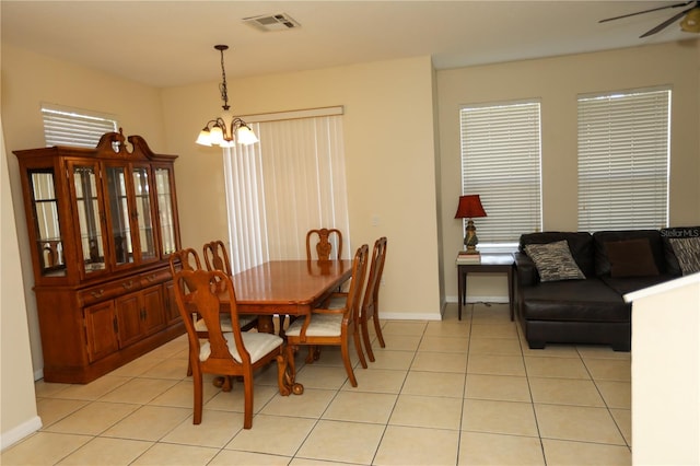 tiled dining room with ceiling fan with notable chandelier