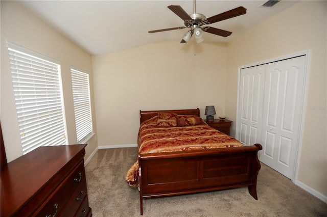 carpeted bedroom with a closet, lofted ceiling, and ceiling fan