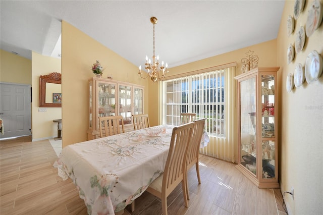 dining space with light hardwood / wood-style flooring, a chandelier, and lofted ceiling