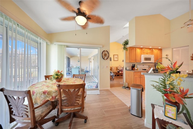 dining space with ceiling fan, light hardwood / wood-style floors, and lofted ceiling