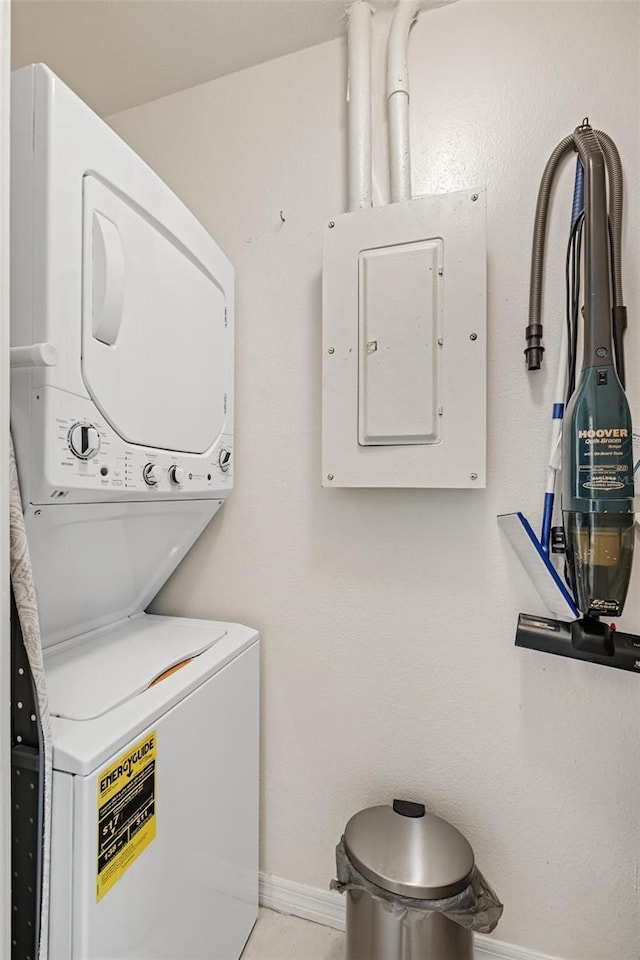 washroom featuring electric panel and stacked washing maching and dryer