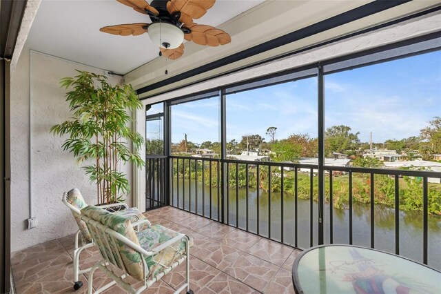 sunroom / solarium featuring ceiling fan and a water view