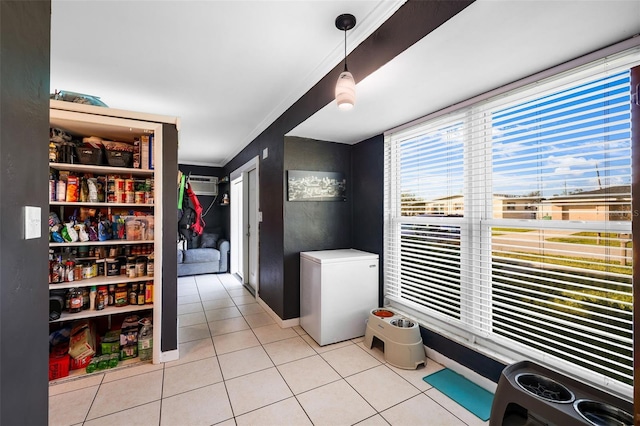 interior space with a wall unit AC, ornamental molding, and light tile patterned flooring