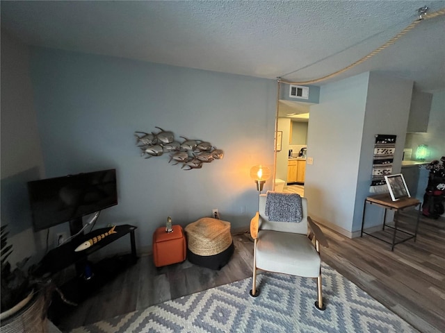 living area featuring a textured ceiling and hardwood / wood-style floors