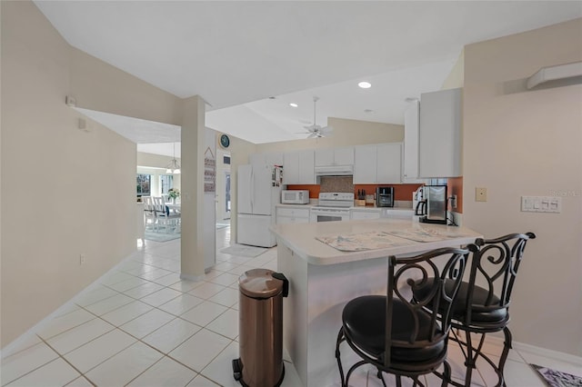 kitchen featuring white appliances, a kitchen bar, kitchen peninsula, vaulted ceiling, and white cabinets