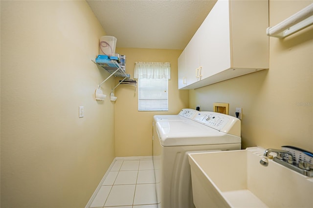 laundry area featuring sink, light tile patterned flooring, cabinets, a textured ceiling, and washing machine and dryer