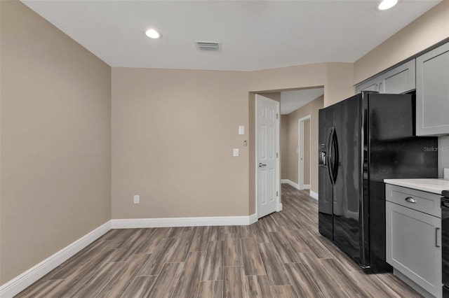 kitchen with light countertops, baseboards, visible vents, and black refrigerator with ice dispenser