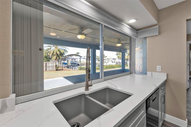 kitchen featuring a sink, recessed lighting, baseboards, dishwasher, and light stone countertops