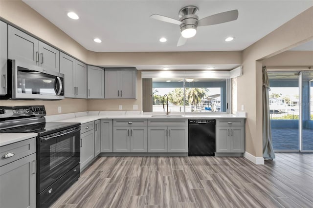 kitchen with gray cabinets, black appliances, light countertops, and a sink