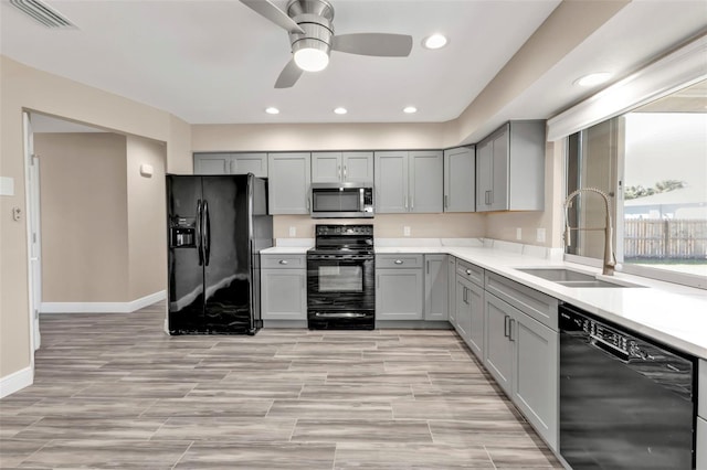 kitchen featuring visible vents, gray cabinets, a sink, black appliances, and light countertops