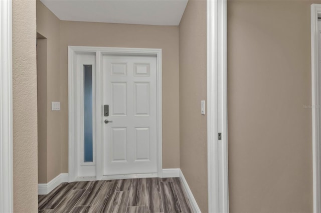 doorway featuring baseboards and dark wood-style flooring