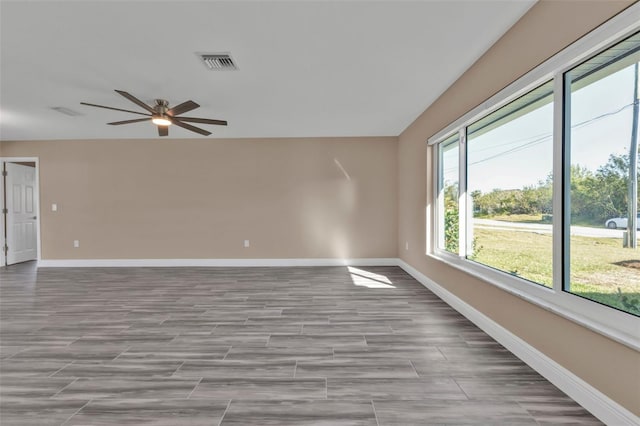 unfurnished room with wood finish floors, baseboards, visible vents, and ceiling fan