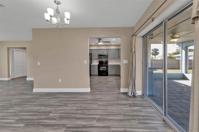 interior space featuring visible vents, ceiling fan with notable chandelier, baseboards, and wood tiled floor