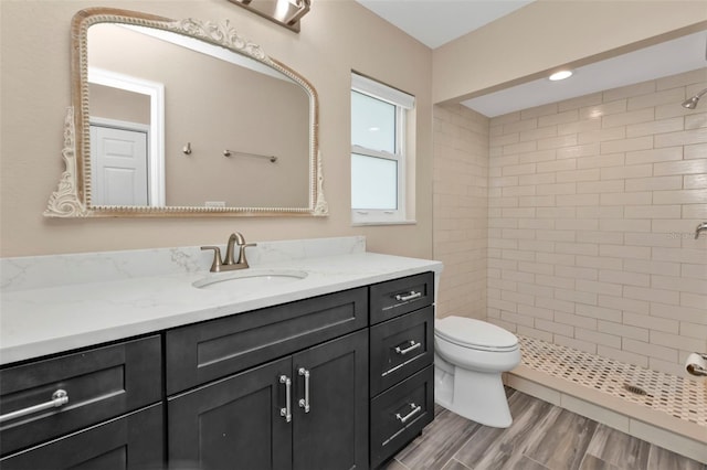 bathroom featuring toilet, a stall shower, vanity, and wood finished floors