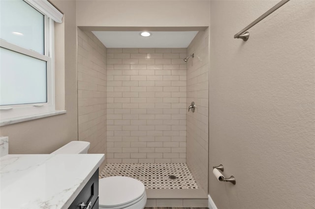 bathroom with vanity, toilet, a textured wall, and a stall shower