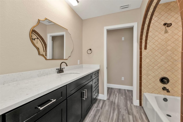 bathroom featuring vanity, visible vents, baseboards, wood finish floors, and bathing tub / shower combination