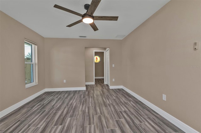 spare room with wood finish floors, visible vents, baseboards, and a ceiling fan