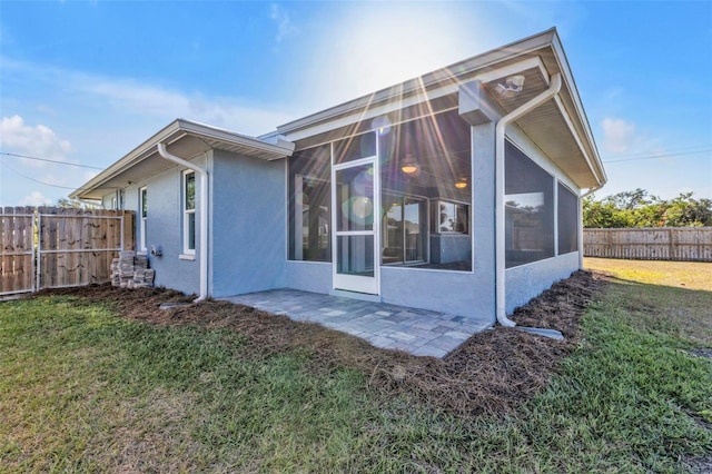 back of house with a patio, a yard, a sunroom, stucco siding, and fence private yard